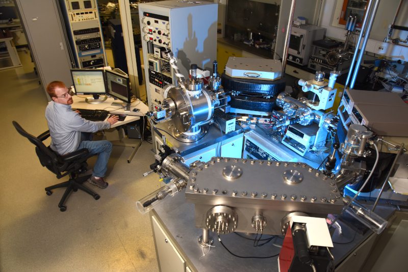 a man in front of a computer while looking at complex labratory instruments