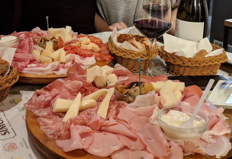 A photograph of two plates of salumi and cheese.
